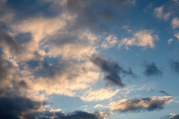Fototapeta na wymiar Cloudy sky in golden sun rays in sunset or sunrise, natural background