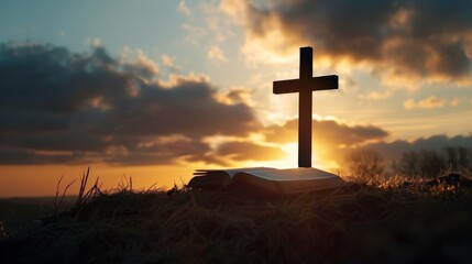 Silhouetted cross on a hill with sunrise and open Bible
