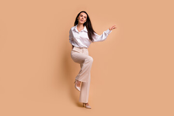 Fototapeta na wymiar Full length photo of excited pretty lady dressed white shirt having fun dancing empty space isolated beige color background