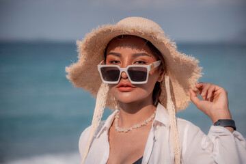 Portrait beautiful Asian woman wearing Bikini ,white t-shirt, sunglasses and straw hat at beach on...