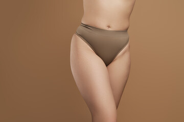 Cropped image female body in green underwear isolated over beige color background. Well-being....