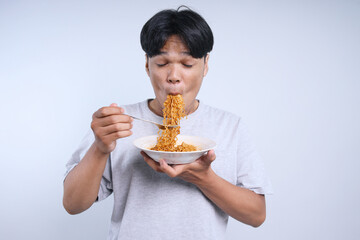 Young Asian man enjoying eating fried spicy noodles with fork