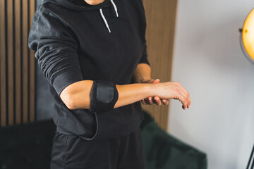 woman wearing an elbow support brace at home, rehabilitation process. High quality photo