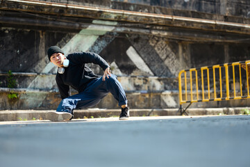 Shot of active male dancer performing breakdance in the street outdoors