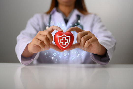 Doctor in white coat holding red heart shape in hand Medical, health insurance and cardiology concept