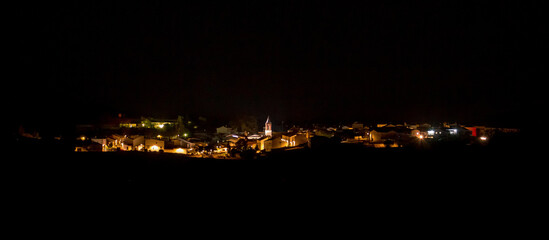 Imagen panorámica nocturna del pueblo, El Granado, Huelva, Andalucía, España. Calles del pueblo iluminadas por las farolas del municipio con el campanario de la iglesia en el centro. © AngelLuis