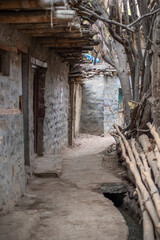 View of village mud path in Turtuk,Ladakh. Street with white soil and stone build houses.Dry logs lying at one corner. Traditional architecture,Turtuk,Ladakh , India countryside.