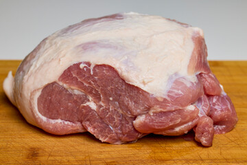 A piece of pork on a wooden chopper.