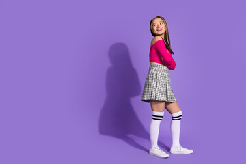 Full size photo of lovely nice girl dressed pink top checkered skirt arms crossed look at sale empty space isolated on purple background