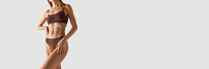 Banner. Cropped photo of woman in brown lingerie against grey studio background with negative space to insert text. Concept of beauty treatments, dieting, female health, spa procedures. Ad
