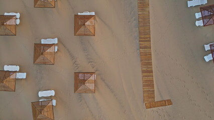 Top view wicker umbrellas and lounge chairs at sand. Aerial shot resort beach