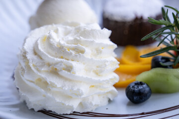 Swirl of fluffy whipped cream with fruit in the background