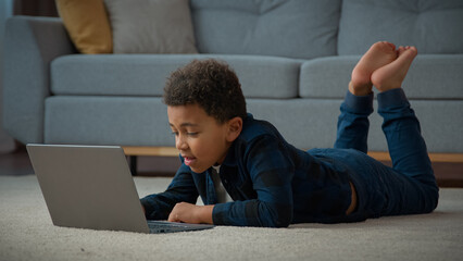 African American kid boy ethnic school pupil studying online from home watching web class lesson...