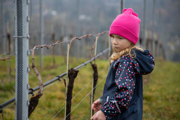 A child stands among vineyards and a beautiful landscape