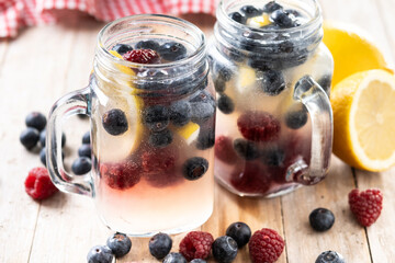 Fresh berry drink with blueberries and raspberries and lemon on wooden table.