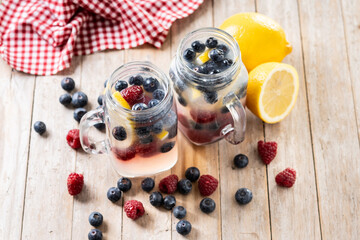 Fresh berry drink with blueberries and raspberries and lemon on wooden table.