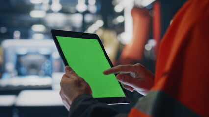 Specialist hands holding green screen tablet at manufacturing facility close up.
