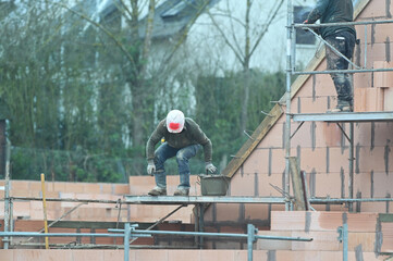 ouvrier maçon sur un chantier de construction d'une maison d'habitation - 753568686