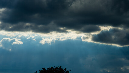 Sunlight against the background of dark rain clouds in the evening. - 753568892