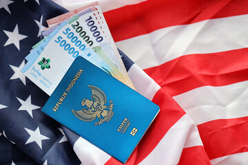 Blue Republic Indonesia passport and money on United States national flag background close up....