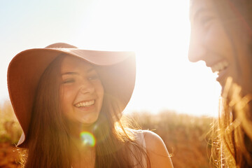 Women, friends and nature with summer hat for travel, holiday and vacation together in lens flare....