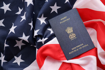 Blue Indian passport on United States national flag background close up. Tourism and diplomacy concept