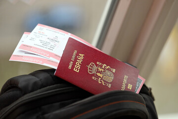 Red Spanish passport of European Union with airline tickets on touristic backpack close up. Tourism...