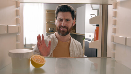 POV point of view from inside refrigerator hungry Caucasian man at kitchen open empty fridge with...