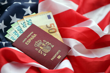 Red Spanish passport of European Union and money on United States national flag background close up. Tourism and diplomacy concept - obrazy, fototapety, plakaty
