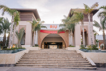 Agadir, Morocco - February 25, 2024 - Entrance of the RIU hotel with palm trees, stairs, and a red...