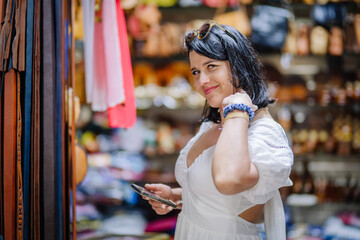 Agadir, Morocco - February 25, 2024 - A woman with sunglasses on her head holding a phone in a market.