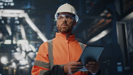 Serious factory supervisor looking at manufacturing making notes tablet close up - obrazy, fototapety, plakaty