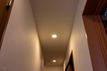 天井の小さなダウンライトで照らされた狭い廊下
