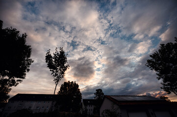 A dramatic sky at sunset, with a blend of clouds and colors over a peaceful residential neighborhood, invoking the day's end serenity