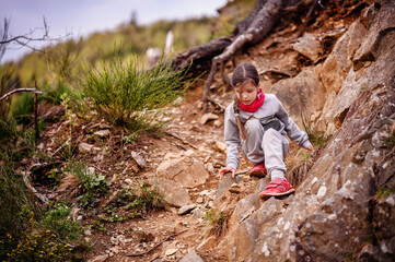 A focused young girl carefully navigates a rocky trail, displaying determination and the spirit of adventure in the great outdoors