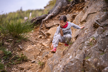 A focused young girl carefully navigates a rocky trail, displaying determination and the spirit of...