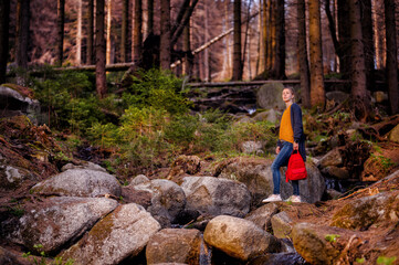 A wanderer finds solace among stone and stream in the heart of the woods, her expression one of...