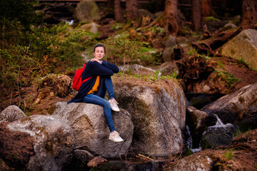 Amidst a rustic forest setting, a young woman finds a moment of reflection while seated on a...