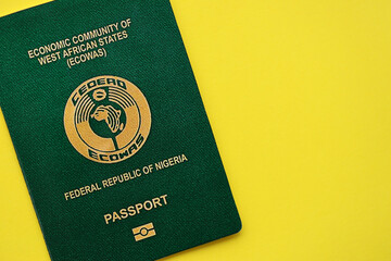 Green Nigerian passport on yellow background close up. Tourism and citizenship concept