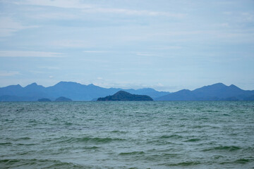 The ocean is calm and the sky is cloudy. The mountains in the background are visible