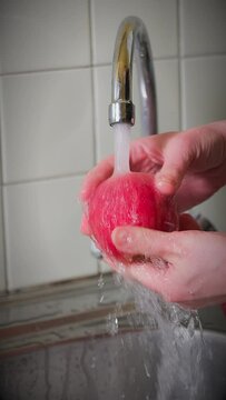 washing an apple in the kitchen sink running water