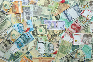 Many banknotes of different currency. Background of big amount of random money bills close up