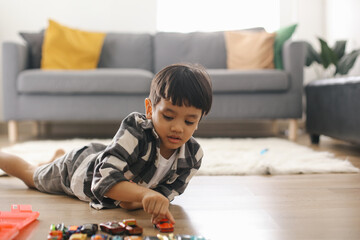 Little Asian kid playing with lots of colorful plastic toys at home