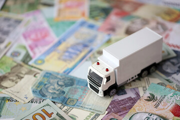 Delivery truck on many banknotes of different currency. Background of trucking or moving concept...