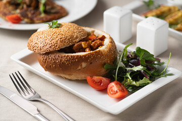 Meat goulash served in bread on a white plate