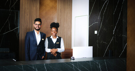 Portrait of polite, professional male and female workers of fancy hotel in uniform. Indian and...