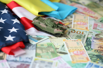 Toy tank on US flag and ukrainian flag on many banknotes of different currency. Background of war...