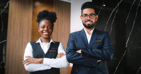 Close up portrait of team of professional polite and hospitable male and female receptionist standing with crossed arm looking at camera and smiling. Attractive happy workers of hotel.