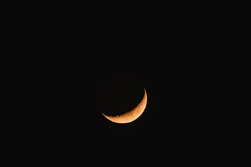 Waxing crescent in the sky, a view from the ground to the illuminated crescent moon.