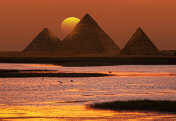 Giza pyramid Complex by the Nile at amazing sunset - Fishermen casting their fishing nets on a boat...